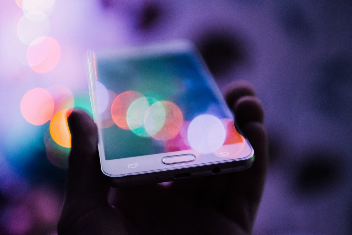 Hand holding a smartphone with colourful light reflections