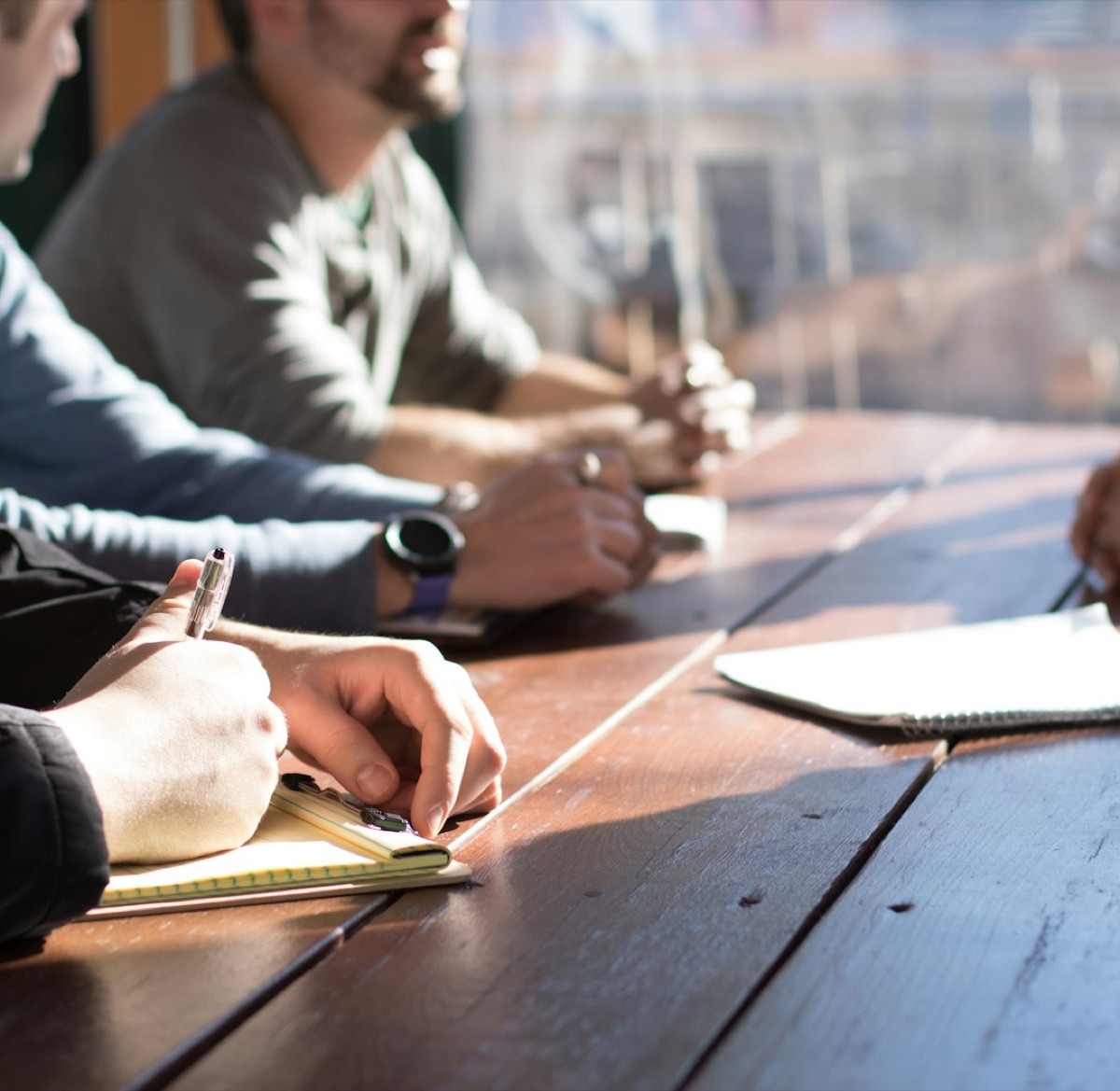 Team taking notes together around a wooden table